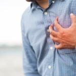 Hand of a man squeezing his heart for having chest pain