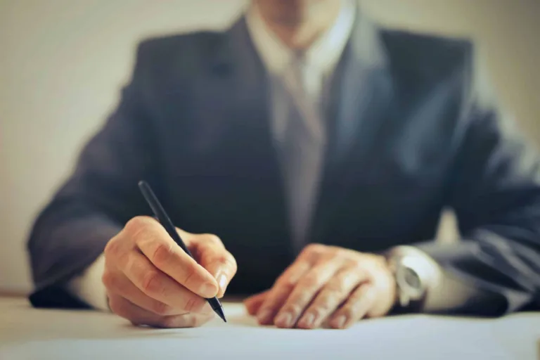 Man in a suit holding black ballpen